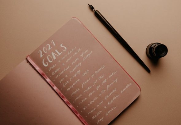 A notebook with '2021 Goals' written in calligraphy, featuring a pen and ink bottle.